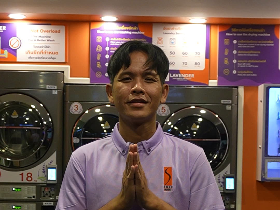 A Lavender staff member greeting with a wai in front of the machines
